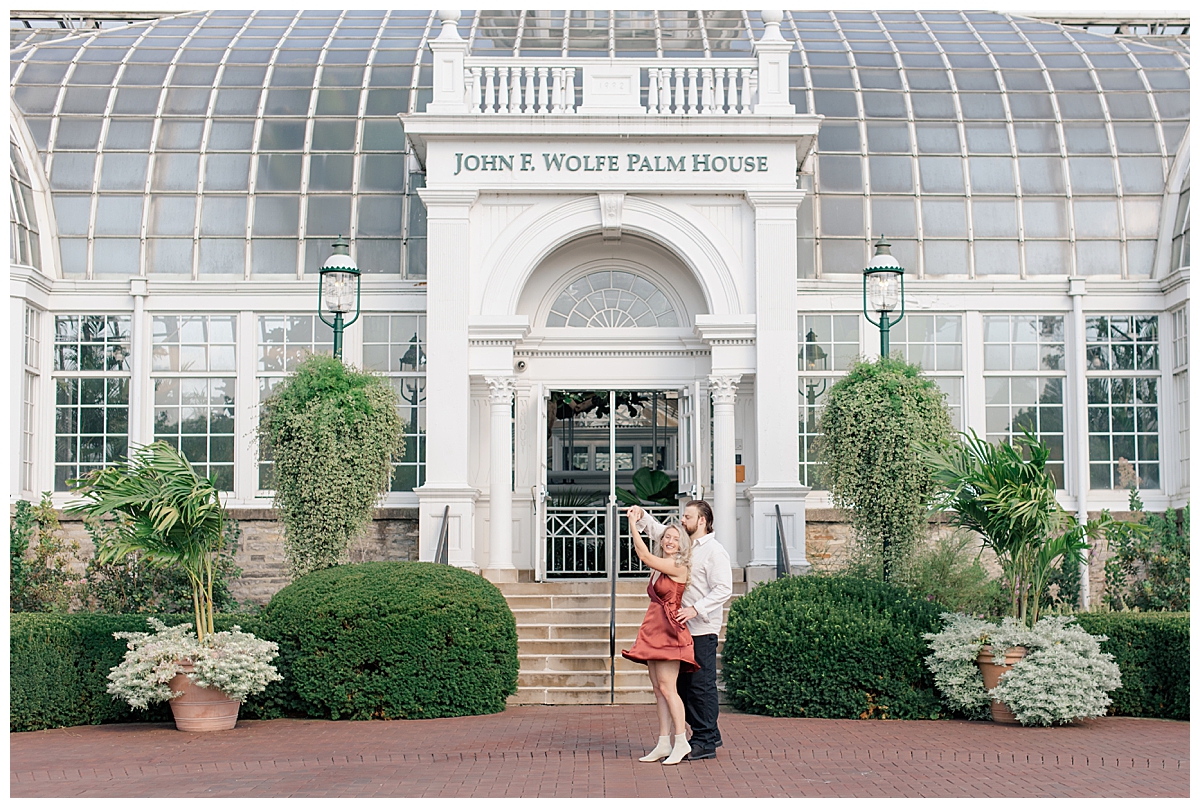 Couple dancing in front of Palm House at Franklin Park Conservatory engagement session taken by Ohio Wedding Photographer Ashleigh Grzybowski