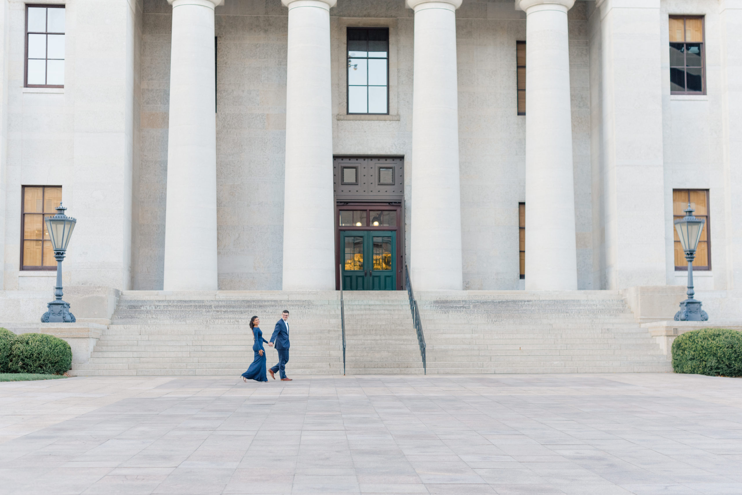 Couple walking in front of Ohio State House in Columbus, Ohio during an engagement session taken by Ohio Wedding Photographer Ashleigh Grzybowski