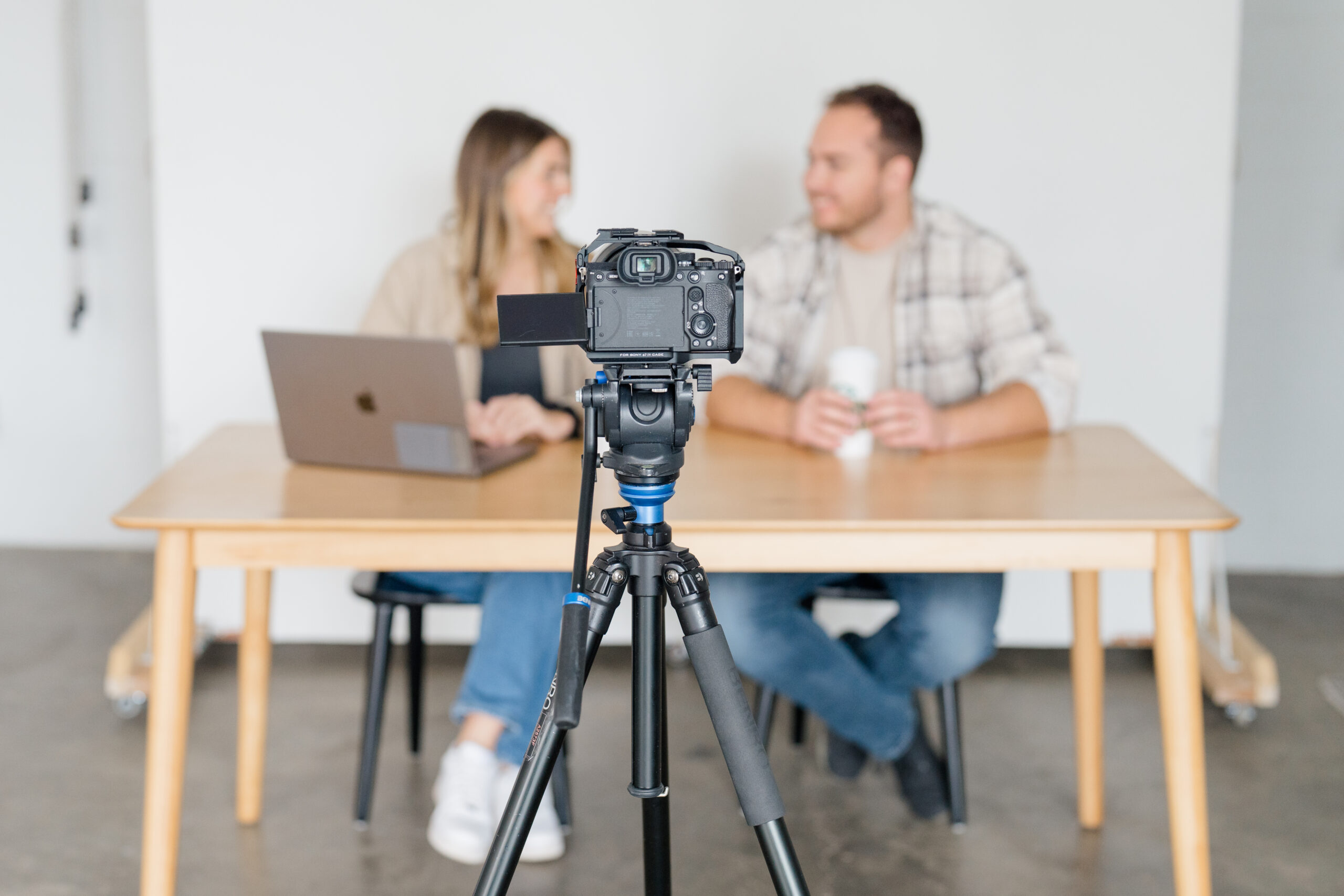 videographers for brand video sitting at a table with a camera in front of them filming