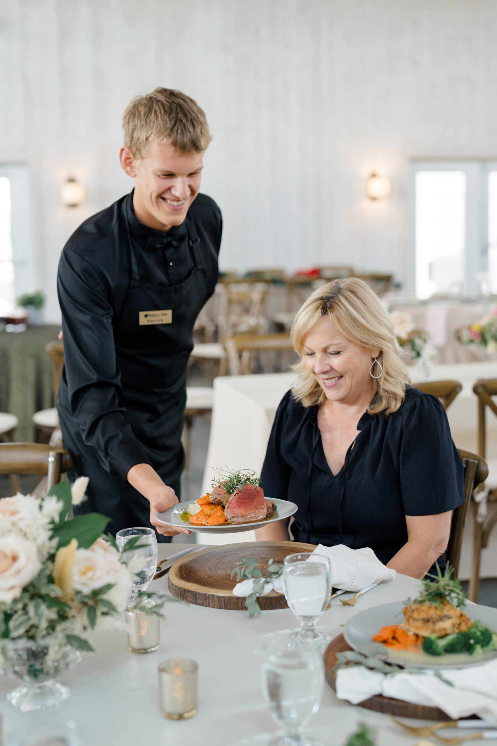 Columbus photographer captures server placing a plate of food in front of a wedding guest for a catering company